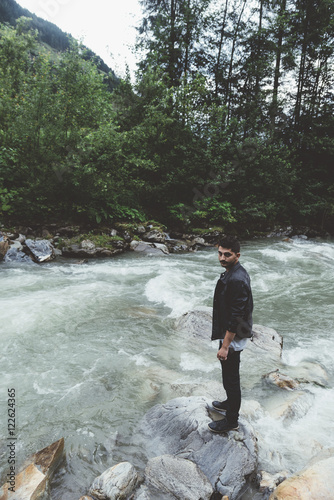 Man on rock on river with t...