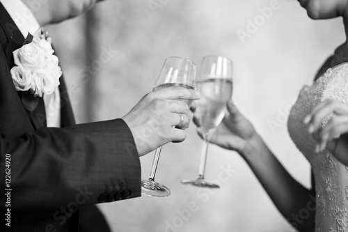 Close-up of newlyweds hands clanging champagne flutes