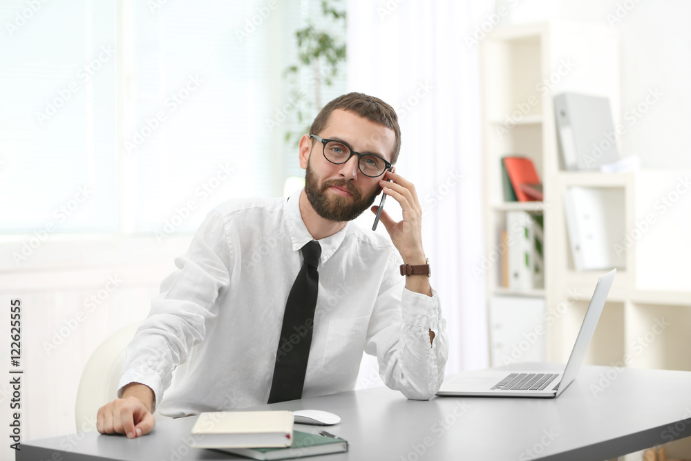 Businessman speaking by mobile phone in office Businessman speaking by mobile phone in office