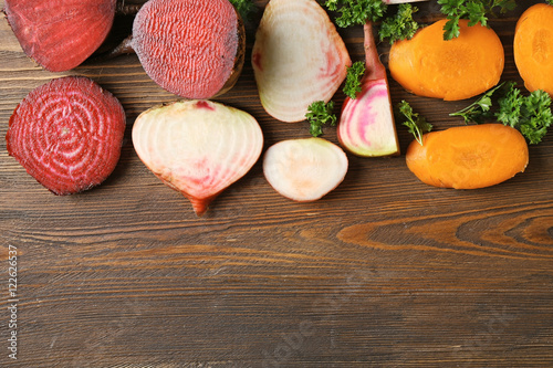 Fresh young sliced beets and carrots with parsley on wooden background