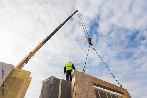 Roofer builder worker with crane installing structural Insulated Panels SIP. Building new frame energy-efficient house photo