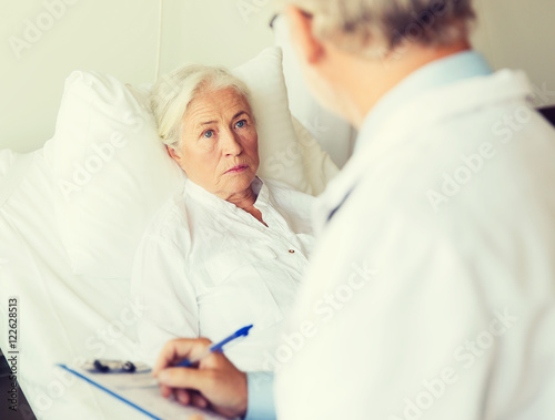 senior woman and doctor with clipboard at hospital