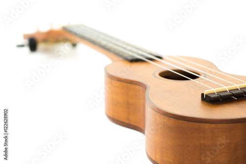 brown wooden ukulele on white background, selective focus