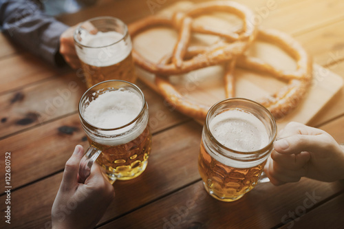 close up of hands with beer mugs at bar or pub