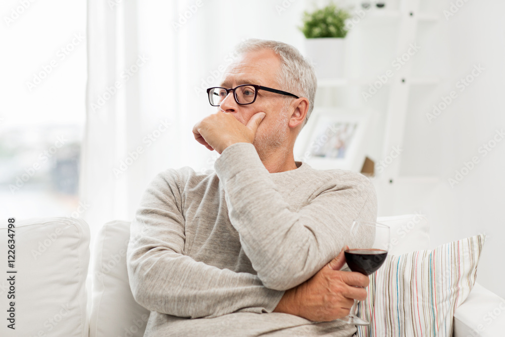 senior man drinking red wine from glass at home