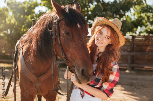 Smiling pretty young woman cowgirl in hat with her horse © Drobot Dean