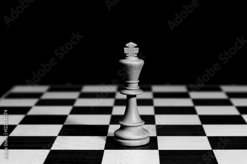 White chess king standing on chessboard alone