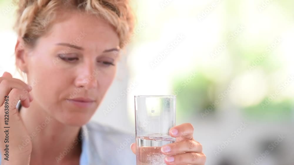 Woman taking aspirine to ease headache Woman taking aspirine to ease headache