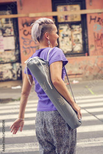 Young woman walking on the street to attend yoga class