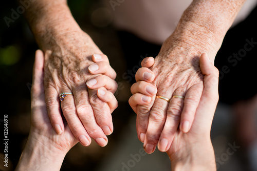 close up of young woman hand holding with tenderness an elderly senior person hands