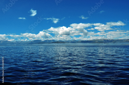 sea lanscape. blue sky, clouds over the surface of sea. mountain on horizon