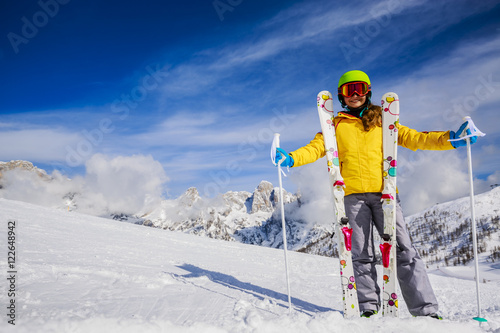 Smiling girl standing with ski and arms spreading wide open on