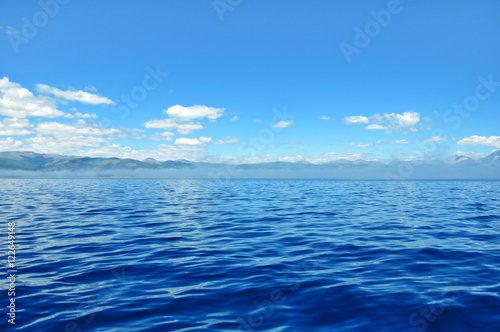 sea lanscape. blue sky  clouds over the surface of sea. mountain on horizon