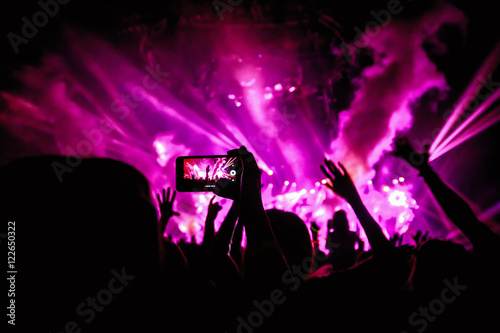 Hand with a smartphone records live music festival, Taking photo of concert stage, live concert, music festival, happy youth, luxury party, landscape exterior - purple light