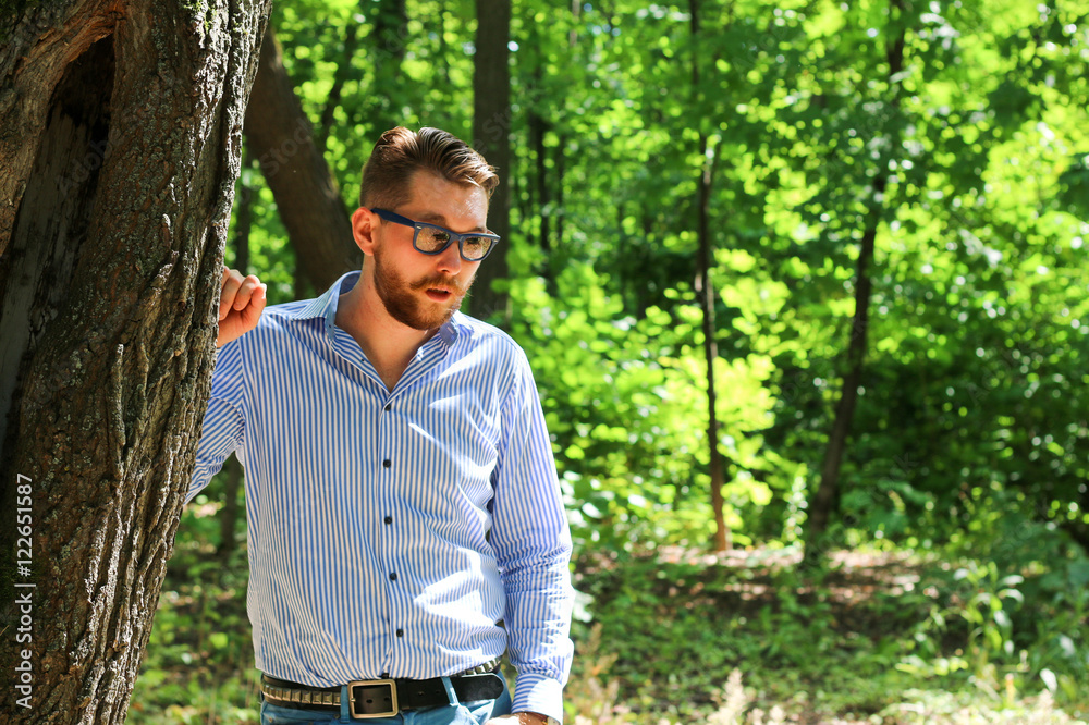Stylish man in sunglasses stands in the forest Stylish man in sunglasses stands in the forest