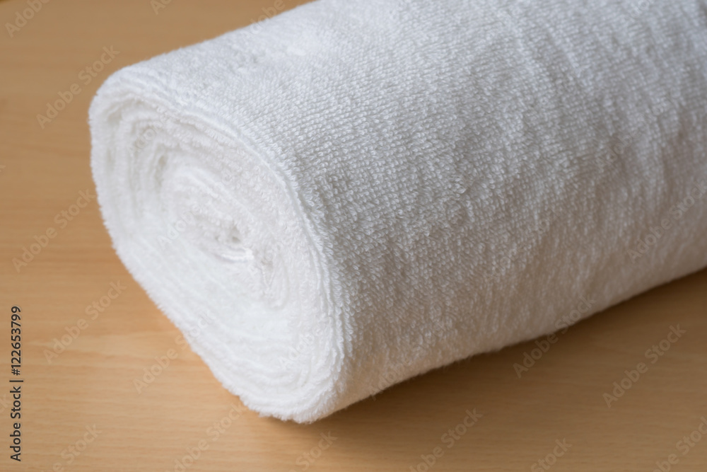 soft bath towel rolled up on wooden table
