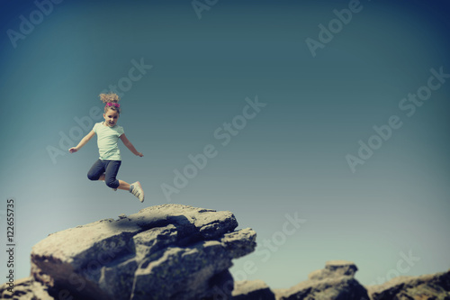 Little girl jumping on stone.