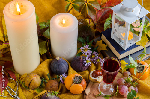 Autumn still life with candles  fruits and books.