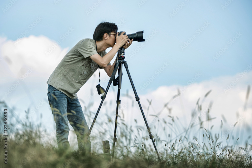 Professional travel on location and nature videographer/photographer (man) photographing nature and landscape outdoor.