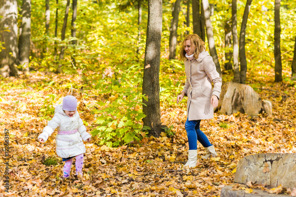 Little girl and her mother playing in the autumn park Little girl and her mother playing in the autumn park