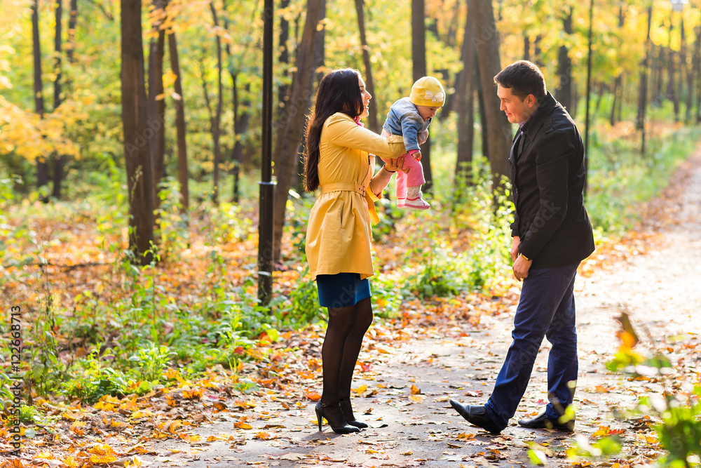 Obraz premium happy young family with their daughter spending time outdoor in the autumn park