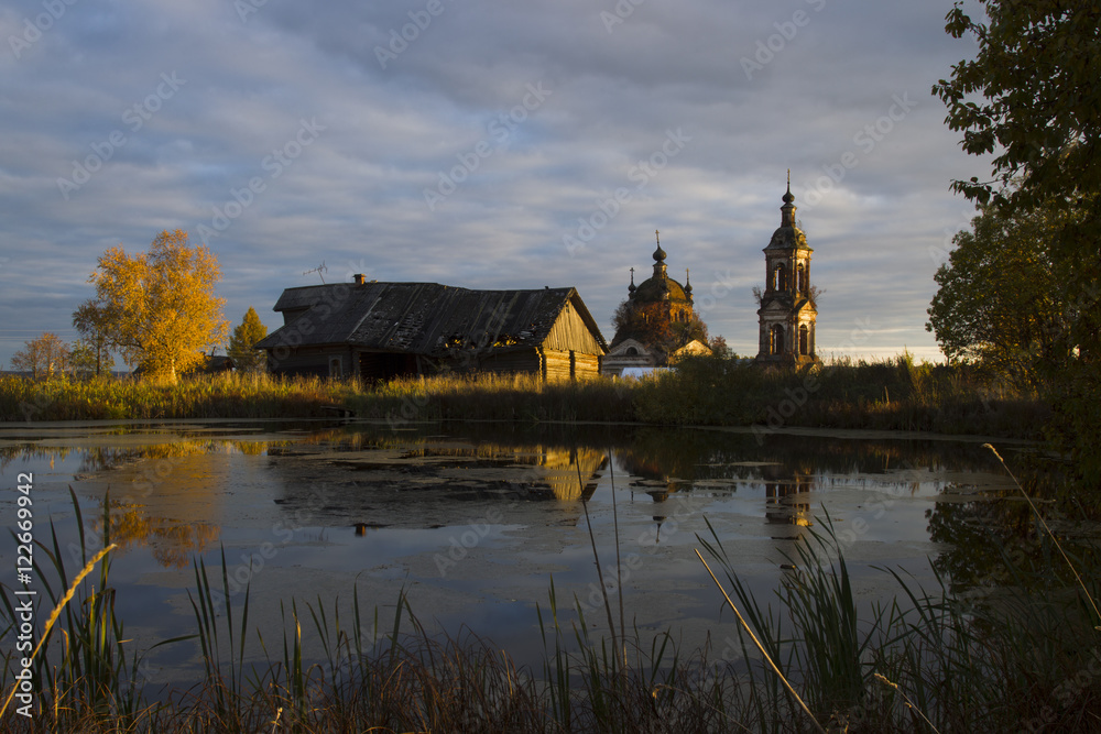 Autumn landscape with a pond, house and church