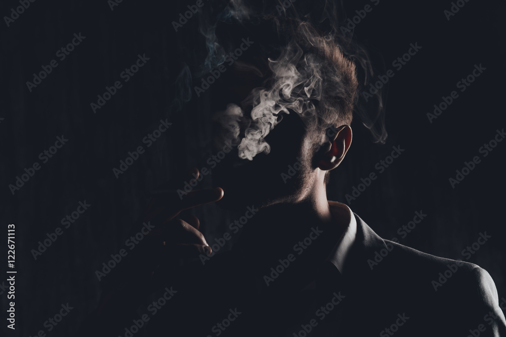 Mystery man with cigar and smoke isolated on black background