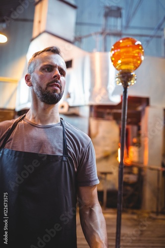 Glassblower shaping a molten glass photo