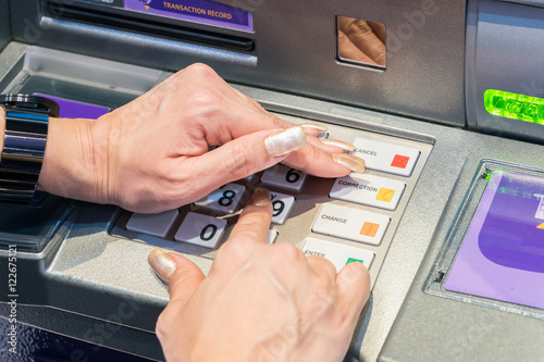 Woman covering her hands whilst entering her PIN at an ATM
