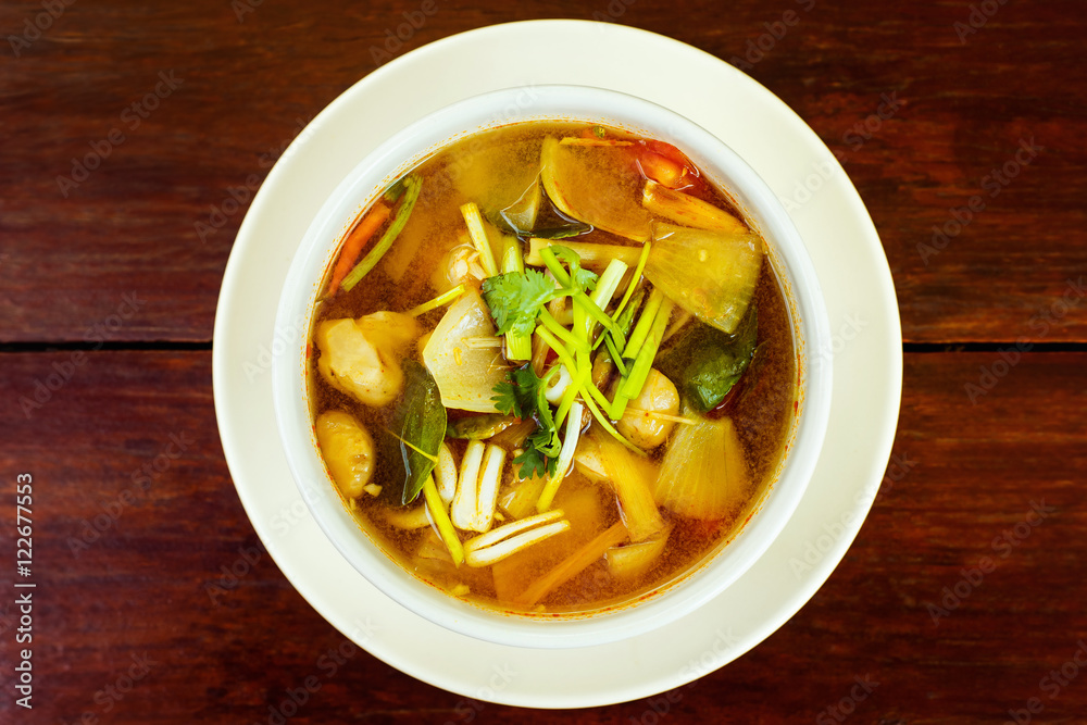 Bowl of fresh spicy hot thai soup Tom Yum at wooden table