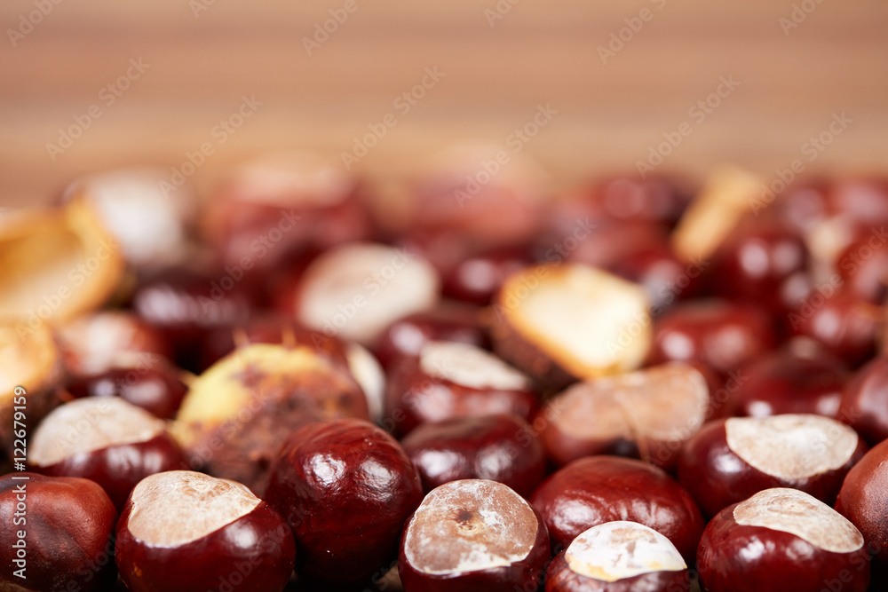 Obraz premium Chestnuts on a wooden table as autumn background