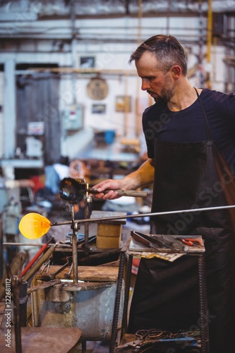 Glassblower forming and shaping a molten glass photo