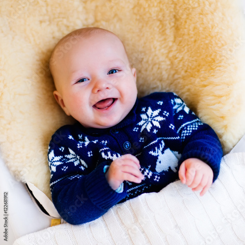 Obraz na plátně Little baby in nordic sweater on sheepskin muff