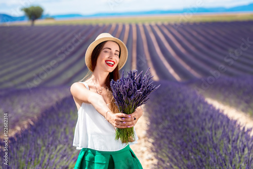 Young woman with lavender bouquet standing on the lavender field in Provence in France