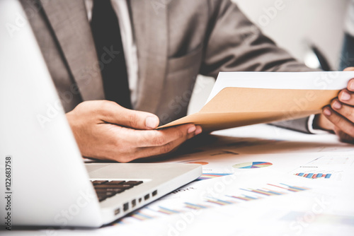 Businessman pulling out business document from brown envelope. photo
