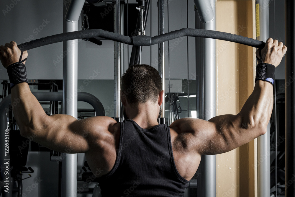 Entrenando en el gimnasio. Hombre con grandes músculos levantando peso mientras entrena en el gimnasio. Ponerse en forma. Entrenando en el gimnasio. Hombre con grandes músculos levantando peso mientras entrena en el gimnasio. Ponerse en forma.