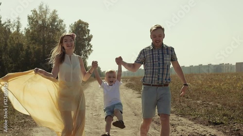 Portrait of happy loving parents holding their son is hands and lifting him up