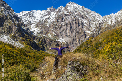 Young woman sitting on stone and looking at snowy peak