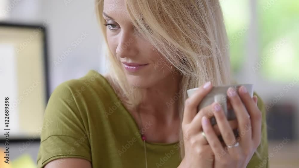 Attractive blond woman drinking hot tea in office Attractive blond woman drinking hot tea in office