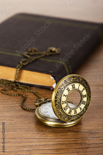 Pocket watch and book against a rustic background