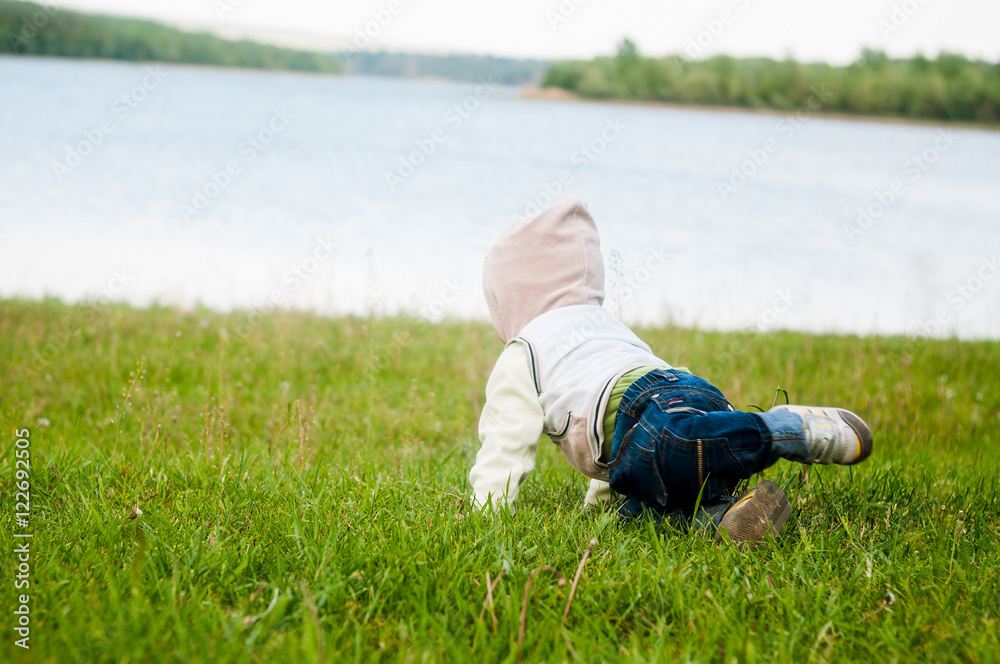 The baby playing in the grass on the river The baby playing in the grass on the river