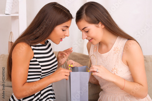 Happy women together looking purchases from shopping bags