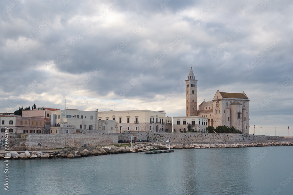 Trani (Apulia, Italy) romanesque cathedral under cloudy sky reflecting in Mediterranean Sea .