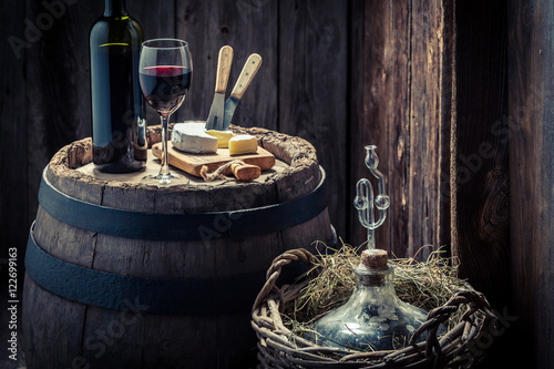 Tasty red wine with camembert cheese and demijohn photo