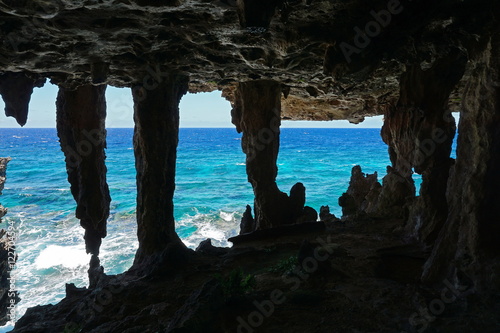 View to the ocean from a cavern with stalactites and stalagmite in a cliff on the sea shore, Rurutu island, south Pacific, Austral archipelago, French Polynesia photo