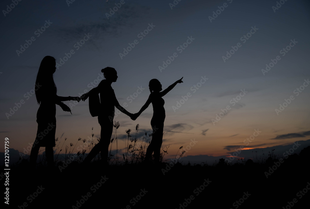 Friends holding hands at sunset.