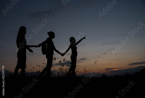 Friends holding hands at sunset.