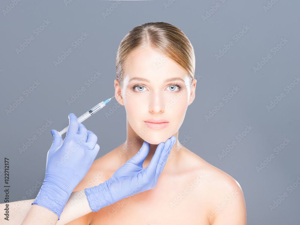 Doctor injecting botox into face of a young woman