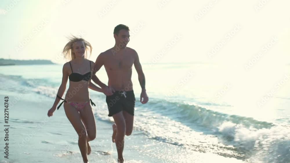 happy couple in swimwear running along the seashore slow motion happy couple in swimwear running along the seashore slow motion