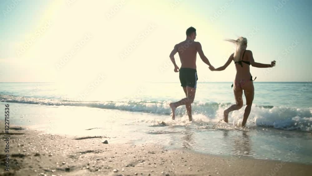 Young beautiful couple running into sea. Slow motion. Young beautiful couple running into sea. Slow motion.